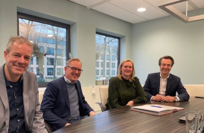 Vier personen die een contract tekenen aan de tafel