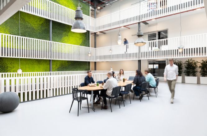 Grote ruimte met lange tafel waar mensen aan werken