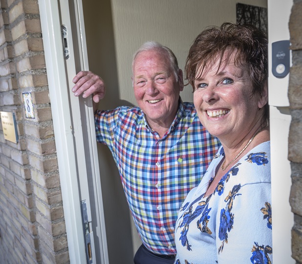 Oude man en vrouw lachend in hun deuropening