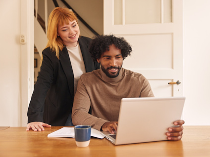 Man en vrouw lachend naar een laptopscherm die op tafel staat