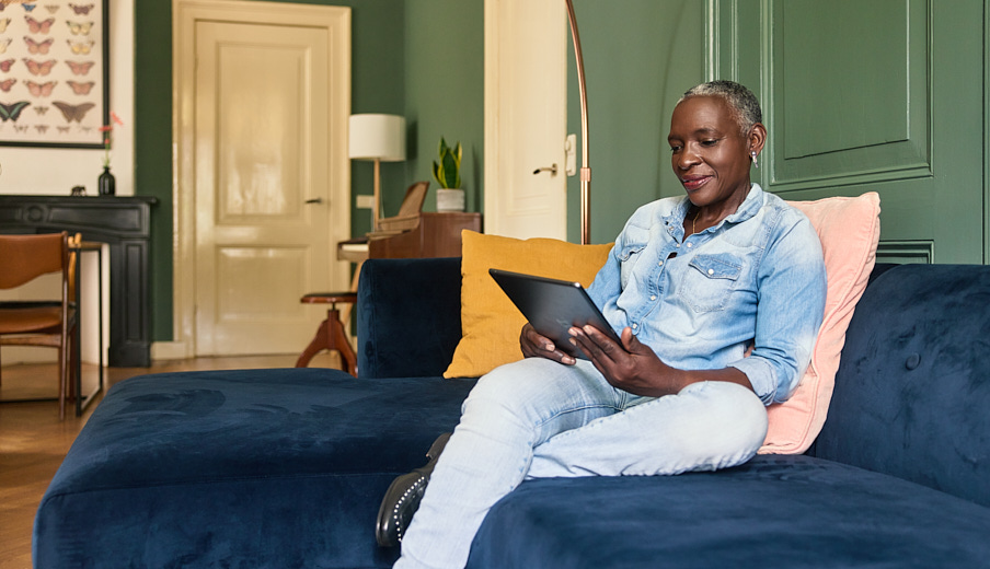 Vrouw die in de woonkamer op de bank zit met haar iPad