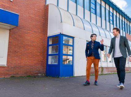 Twee mannen in gesprek wandelend langs een oud pand