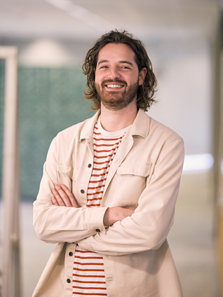Jongeman die glimlacht en met zijn armen over elkaar heen staat