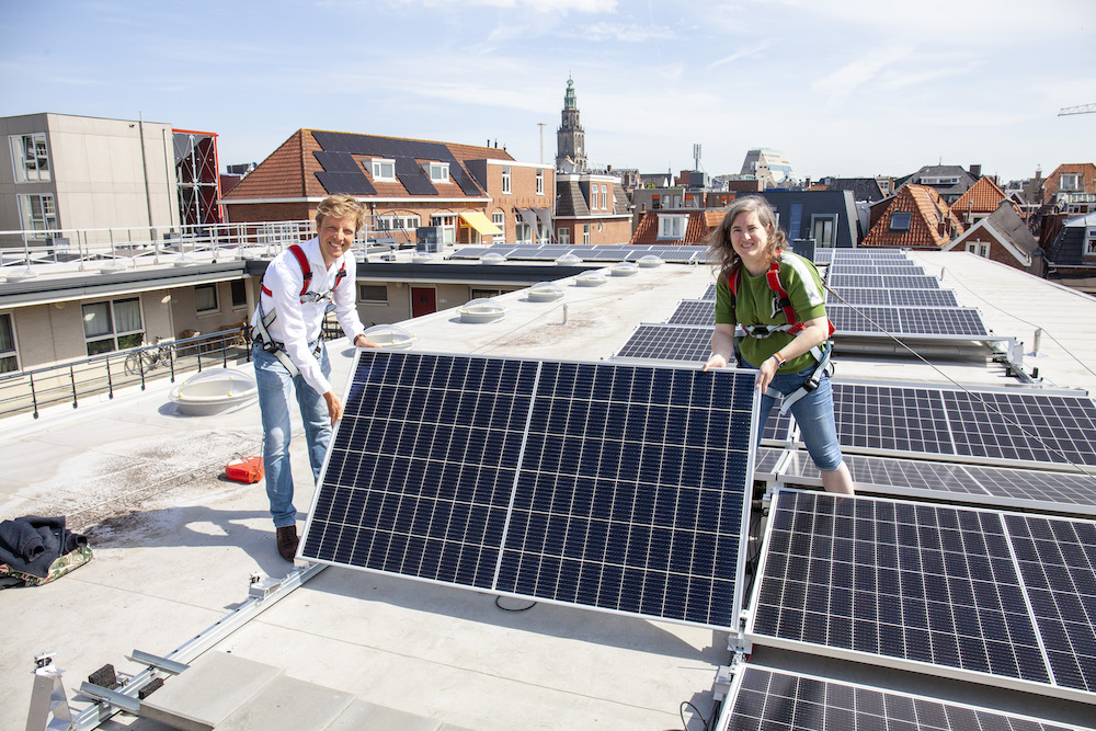 Een man en een vrouw op een dak vol met zonnepanelen om te verduurzamen