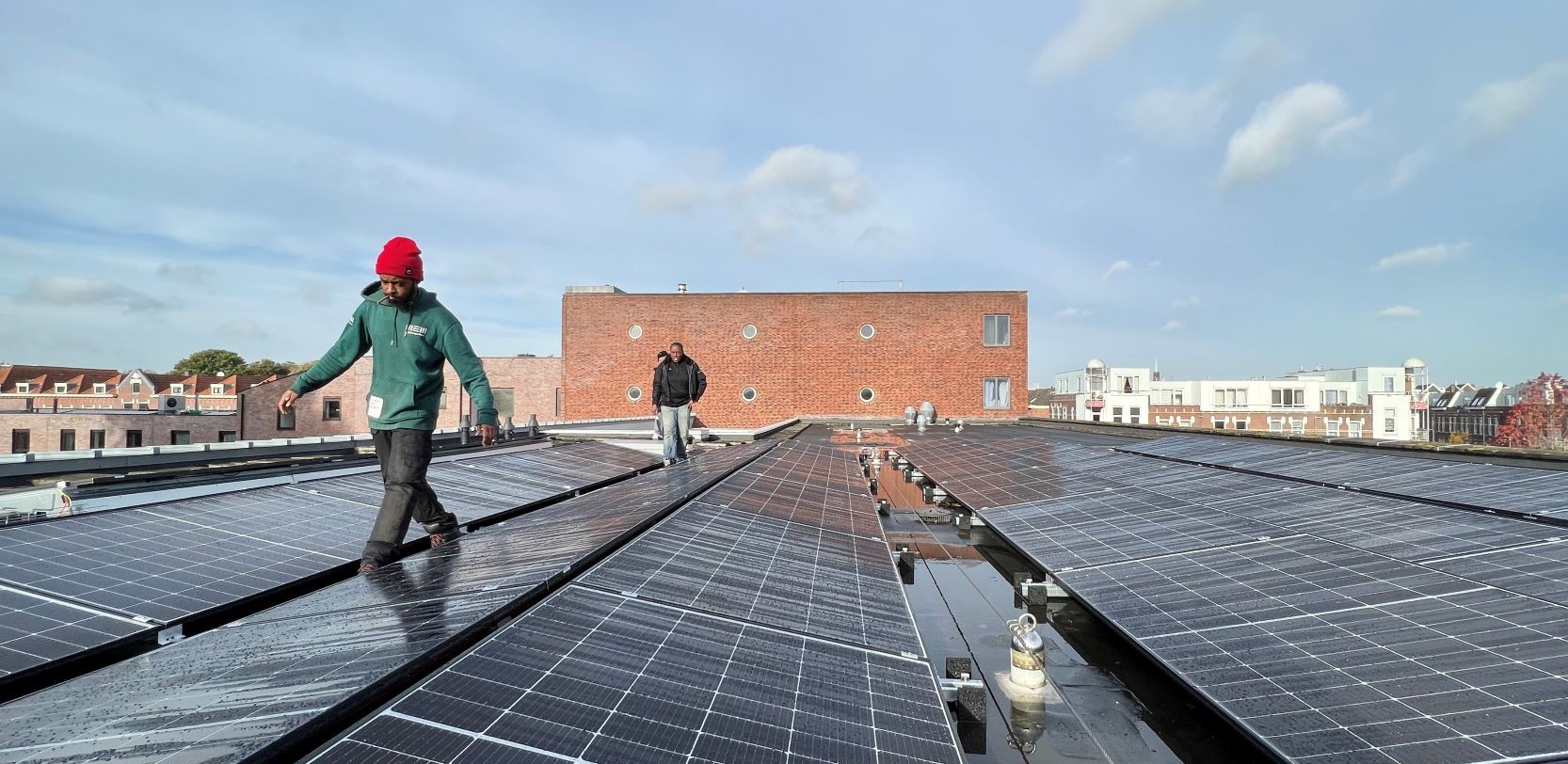 Drie mannen wandelend op een dak dat vol ligt met zonnepanelen