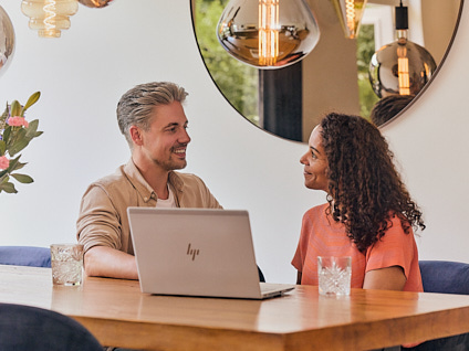 Man en vrouw die samen in gesprek zijn terwijl ze achter hun laptop informatie aan het opzoeken zijn