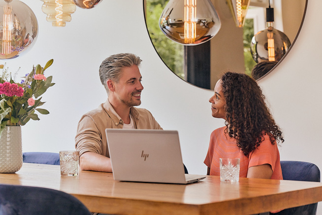 Man en vrouw samen in gesprek terwijl ze op hun laptop informatie aan het opzoeken zijn