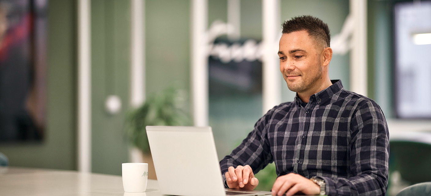 Man lachend aan het werk achter zijn laptop