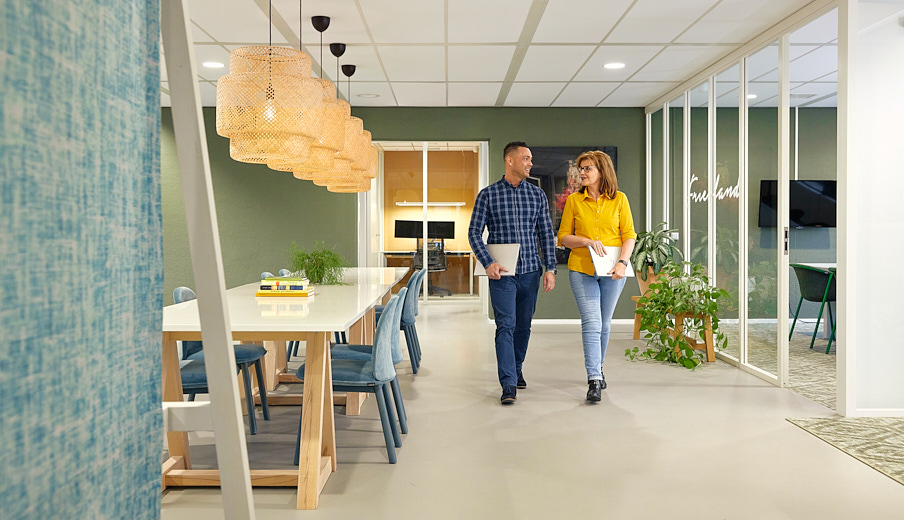 Een man en vrouw die lopen door de gang en ondertussen met elkaar aan het praten zijn