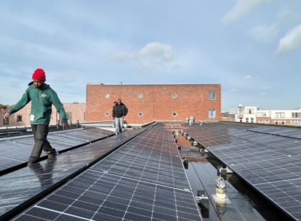 Man lopend op dak met zonnepanelen in Rotterdam Vierambachtschool Energie