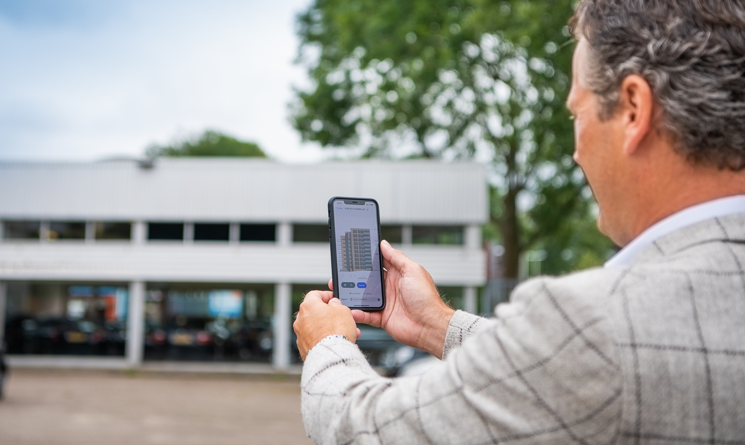 Man met mobiel in handen met op de achtergrond een pand in Zoetermeer voor de Transformatiefaciliteit
