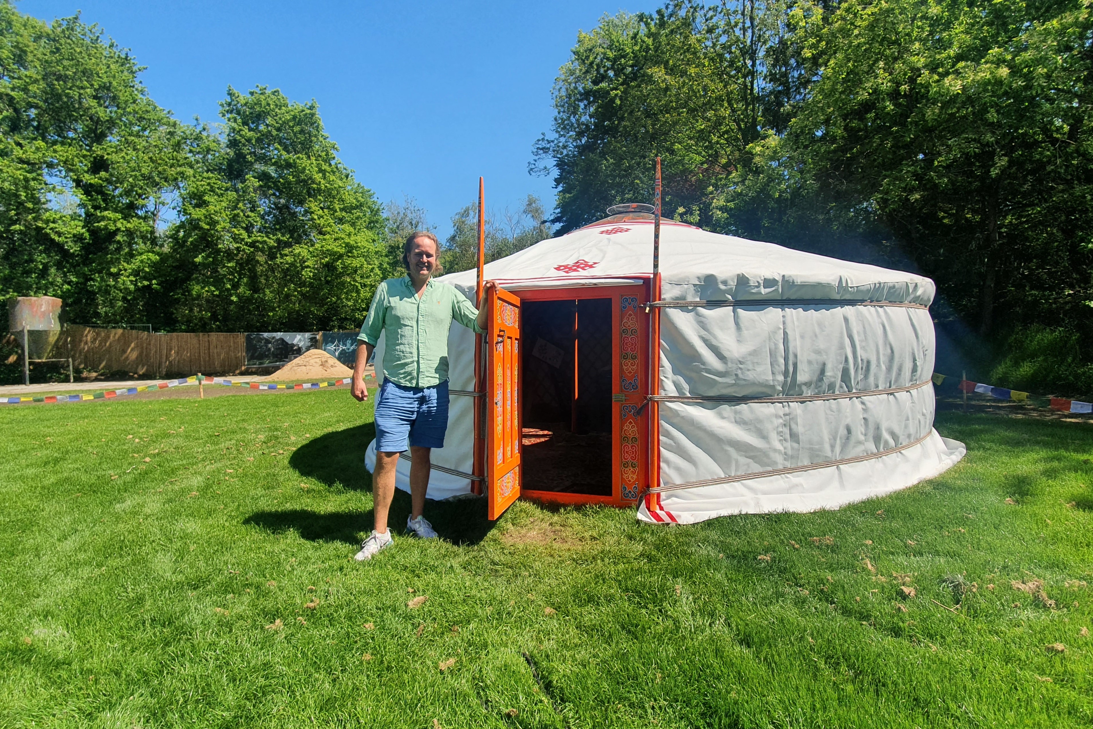 Man op een grasveld naast een tent met deur