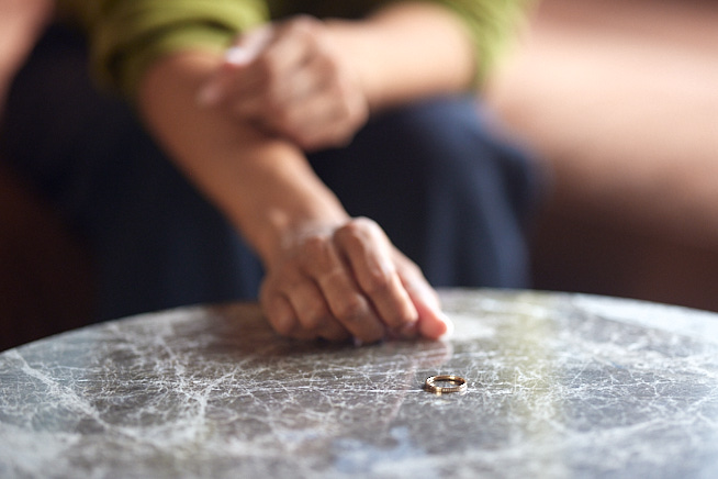 Handen van een vrouw die net haar ring af heeft gedaan en op tafel heeft gelegd