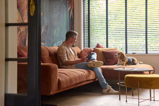 Man met tablet in handen zittend op de bank met zijn hond