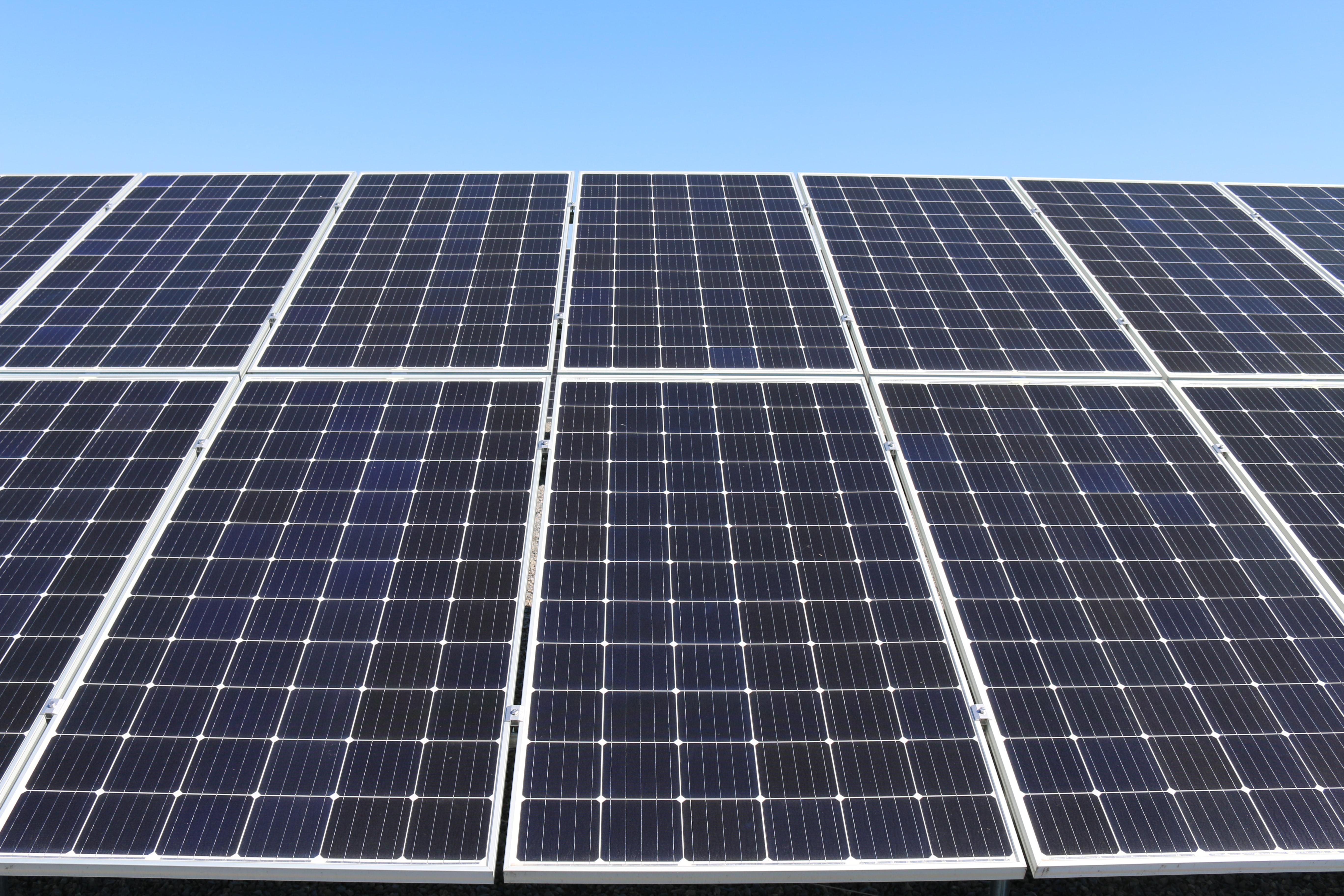Meerdere zonnepanelen op een rij met een blauwe lucht als achtergrond