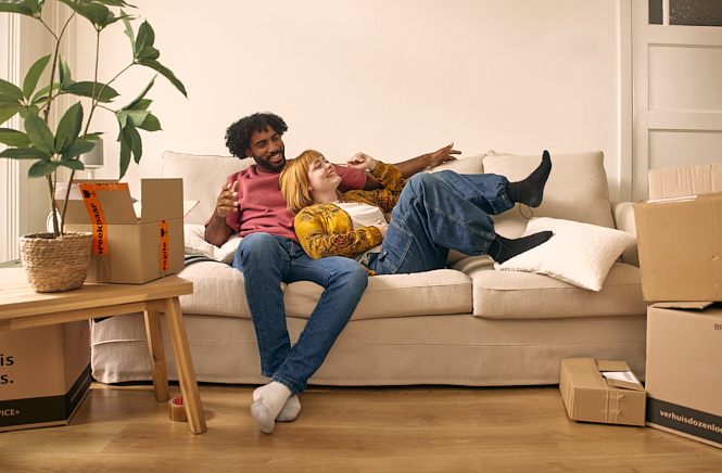 Man en vrouw lachend en onderuit gezakt op de bank