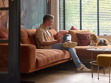 Man zittend op de bank met zijn hond en een tablet in zijn handen