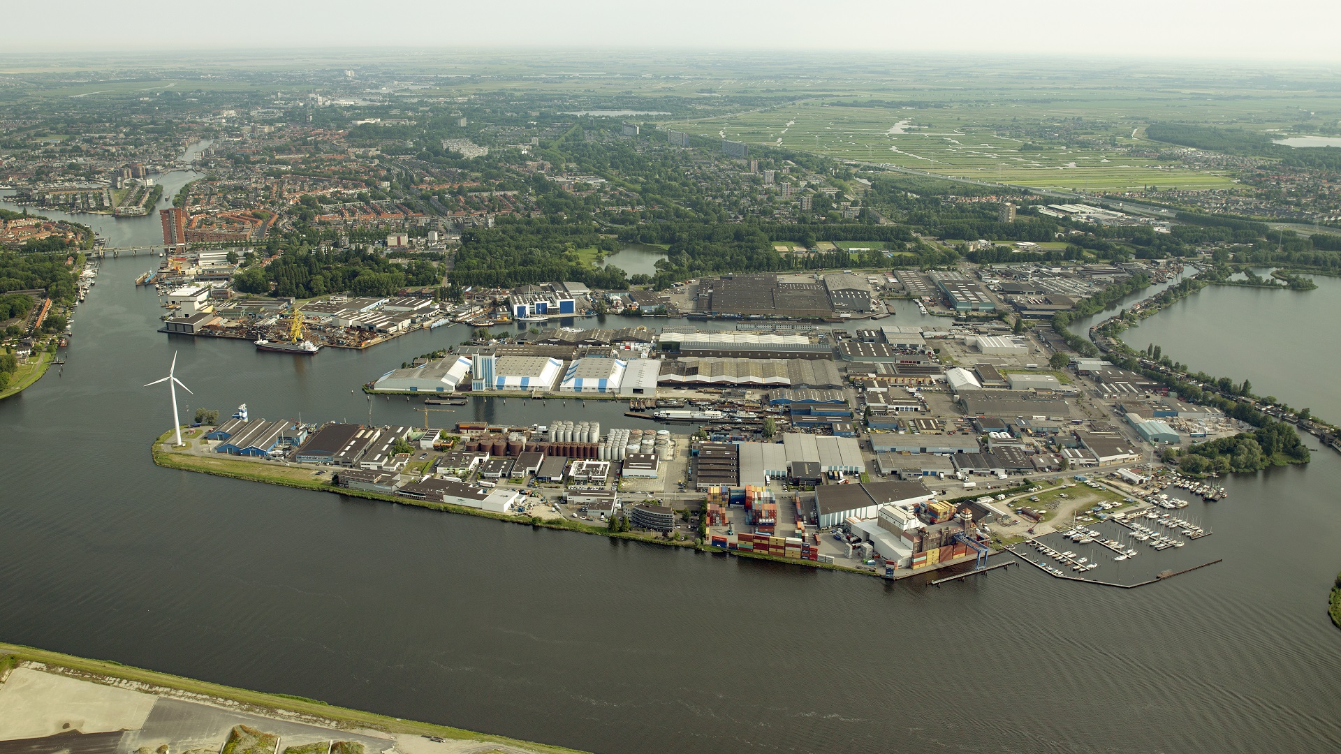 Luchtfoto genomen in Nederland waar je water, gebouwen, een haven en windmolens ziet